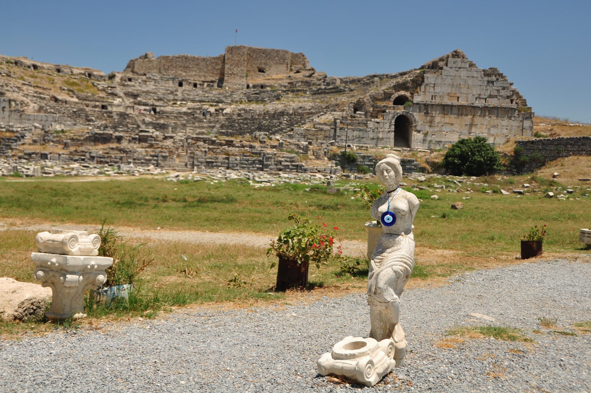 Yol kenarında devrilmiş bir heykelle antik bir tiyatro