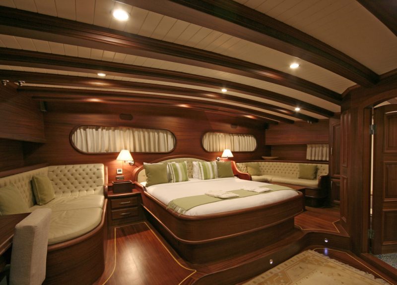A wood-panelled cabin aboard the gulet, with a double bed and a sitting area.
