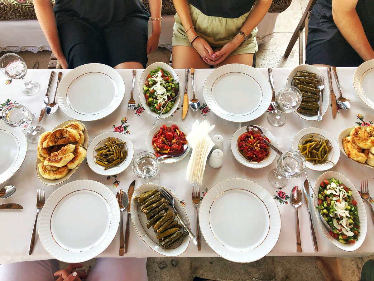 A table set with Turkish meze, stuffed vine leaves, tomato salad and roasted peppers, seen from above