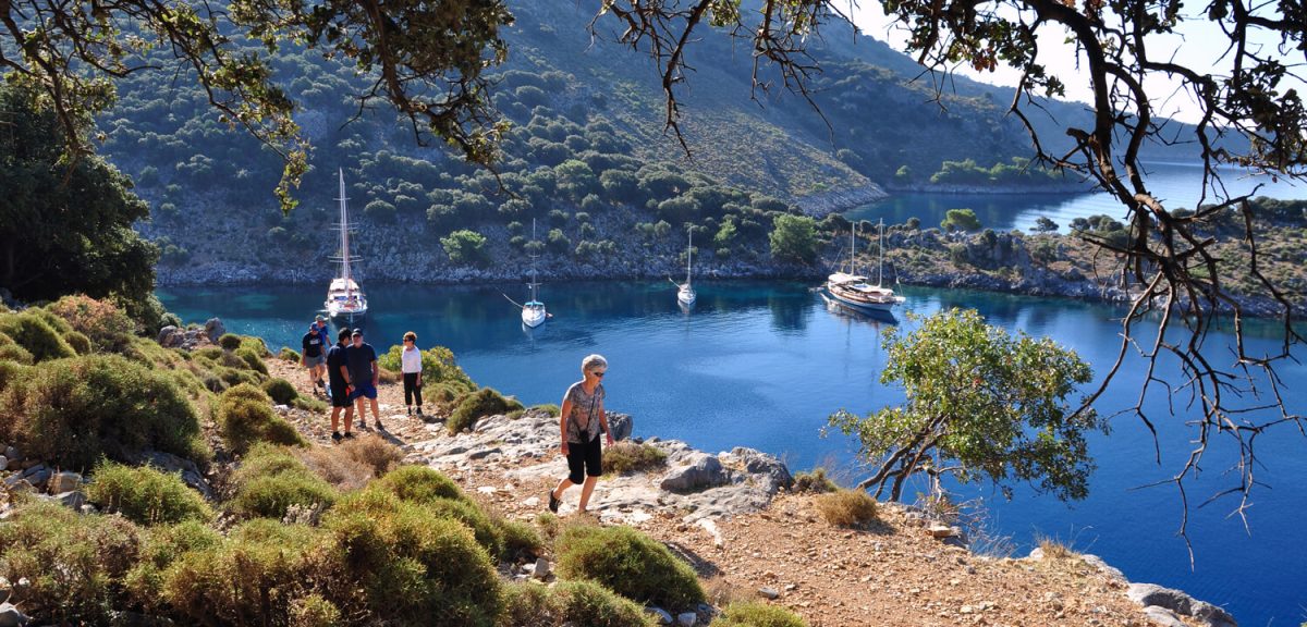 Walkers on a coastal path above the Gulf of Gocek, gulets at anchor below
