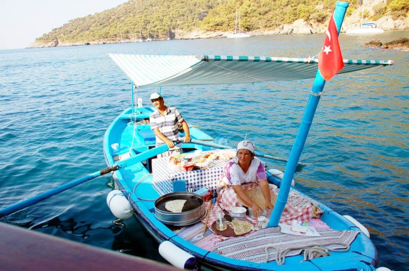 A local vendor preparing gozleme from a small boat alongside.