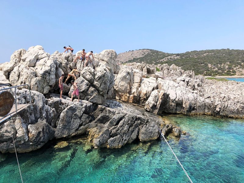 Guests climbing the rocks at a swim stop, with clear water below.
