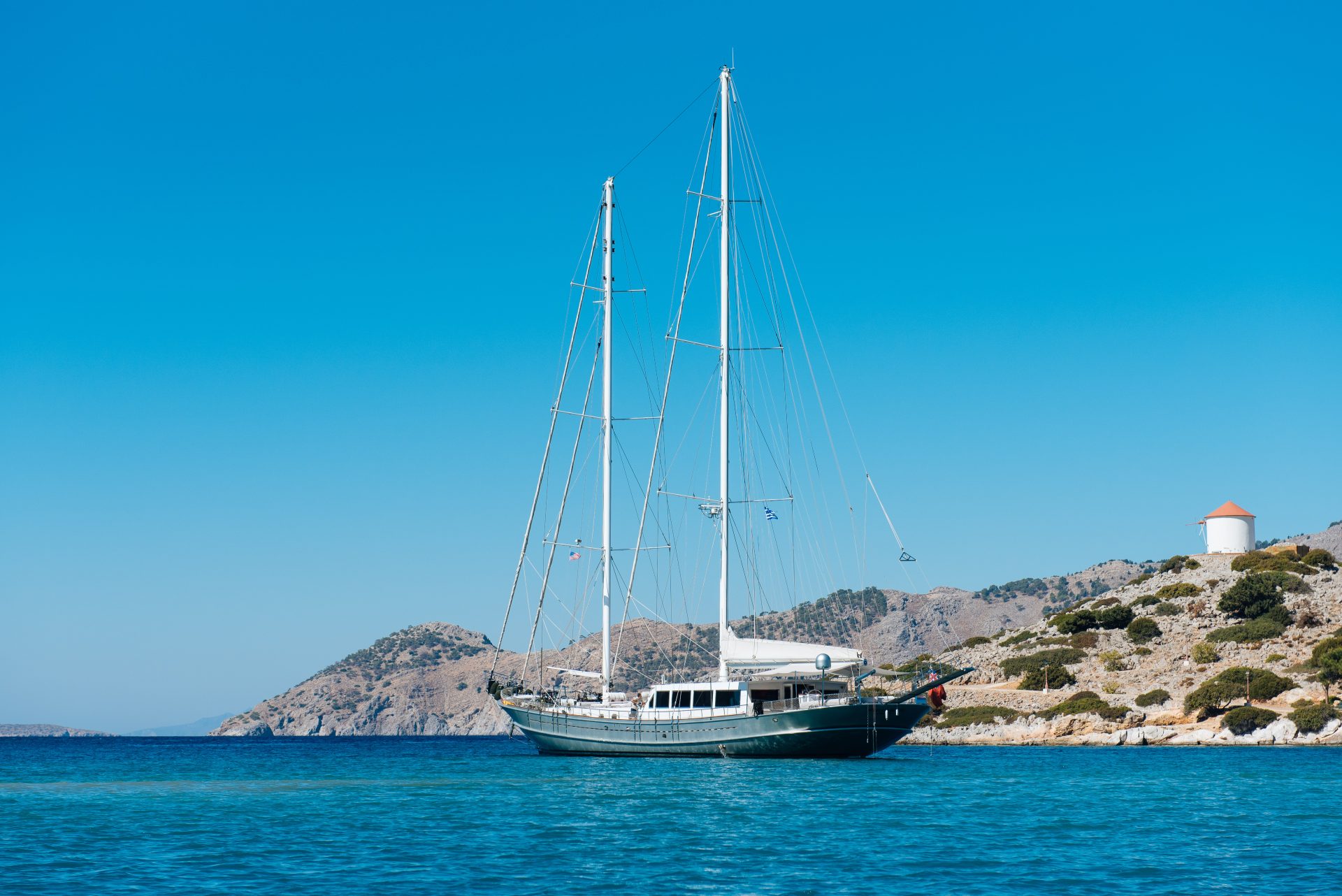 A gulet at anchor off a Dodecanese headland, a windmill on the point