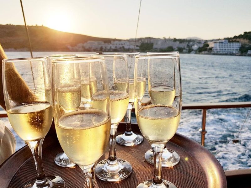 Glasses of sparkling wine at sunset, with the coast in the background.