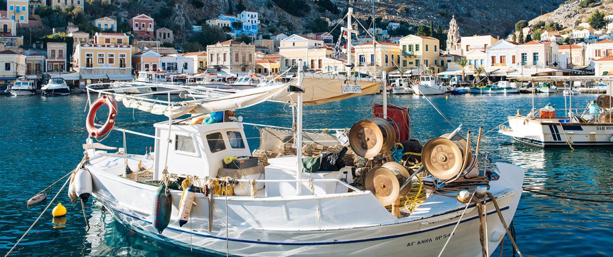 A fishing boat moored below the painted houses of Symi harbour
