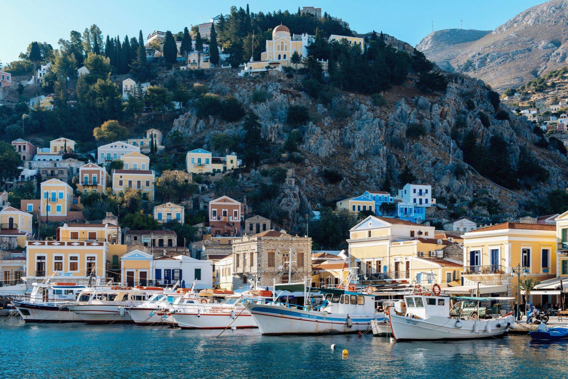 Denizden Symi limanı, balıkçı teknelerinin üstünde yamaca dizilmiş evler